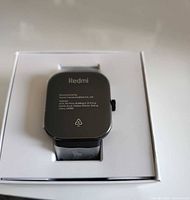 Back of Redmi Watch 4 seated in white tray, protective film attached