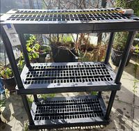 Front view of black 3-tier plastic shelf showing overall structure