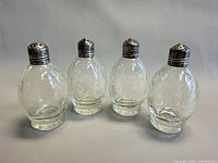 Front view of four glass shakers with sterling caps