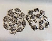 Both metal belts coiled to show link designs and clasps