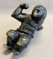 Front view of soapstone hunter sculpture showing raised arm and facial detail