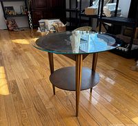 Full view of coffee table showing glass top, wood shelf, legs