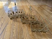 Three gold wire baskets arranged on wood floor