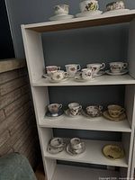 Shelved view showing multiple teacup and saucer sets across three shelves
