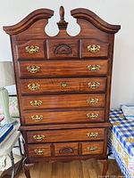 Front view showing full highboy dresser, drawers, hardware, pediment, finial, legs
