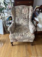 Front view of floral wingback chair showing upholstery pattern, shape and legs
