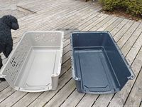 Top and bottom halves of plastic pet crate with wire door lying on decking