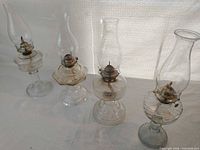 Four glass hurricane lamps side by side