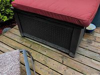 Box with red cushion on top sitting on wooden deck
