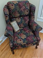 Front view of wingback armchair showing upholstery pattern and pillow