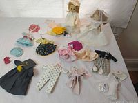 Overall view of two dolls with array of clothing and accessories on tabletop