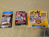 Three sealed Yu-Gi-Oh products on table