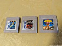 Front view of three original grey Game Boy cartridges showing titles Super Mario Land, Castlevania: The Adventure, Metroid II: Return of Samus
