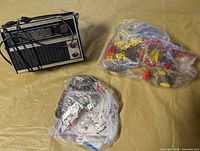 Radio and two bags of construction parts on surface