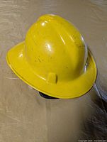 Top and side view of yellow firefighter helmet showing shell shape and scuff marks