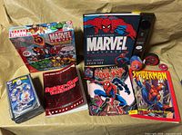 Front view of entire lot showing board game, five books, two media cases and small round toy