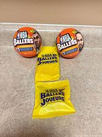 Two sealed NBA Ballers blind balls and two sealed yellow accessory packs arranged on countertop