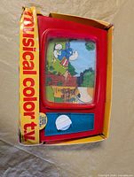 Front of red plastic Smurfs musical color TV toy in original box