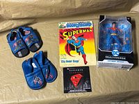 Group shot of all items: boxed figure, comic & record, DVD case, two pairs of children’s Superman shoes