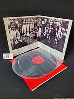 Gatefold jacket open displaying artwork and one vinyl record with red inner sleeve and clear outer