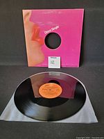 Full shot of record in front of pink Disco Single sleeve