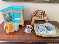 Full lot showing hamster carrier, hamster plush, metal bowl with food, cardboard kennel, husky on bed