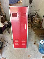 Front view of red-door gray-body metal locker standing on concrete floor