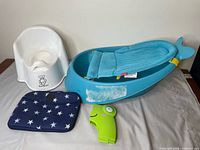 Group shot of potty chair, infant tub with sling, folding potty seat and star changing pad