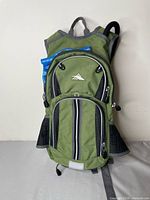 Front view showing green High Sierra hydration backpack, zippers, reflective strip