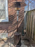 Full view of bronze propane patio heater against brick wall