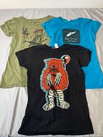 All three T-shirts laid out: olive, blue, black