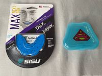 Front view of sealed Sisu Max Next Gen mouthguard package alongside blue Superman logo case