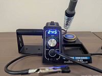 Front of soldering station showing display, control knob and iron in holder
