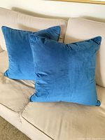 Two blue velvet square throw pillows on sofa