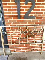 Full view of gold antique brass metal headboard against wall