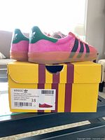 Side and heel view of sneakers on original box showing color, materials, box label