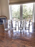 Four clear glass Nespresso mugs lined on table