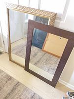 Pair of mirrors leaning against wall showing full view of both frames