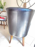 Rear view of one leather wingback chair showing upholstery and leg finish