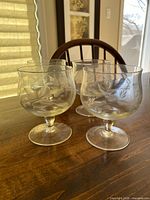 Four etched glass snifters on table showing overall condition