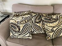 Four paisley throw pillows arranged on sofa