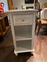 Front view showing marble top, drawer, open shelf and feet