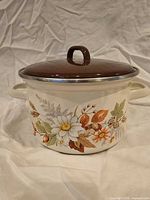 Front view of cream enamel stock pot with floral design and brown lid