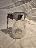 Full view of glass pourer showing fluted body and metal lid with handle