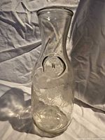 Full view of clear glass carafe showing overall shape and etched design