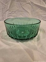 Side view showing emerald green pressed glass bowl with cut-style pattern