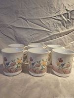 Front view of all six Arcoroc floral milk glass mugs
