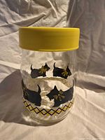 Front view of Carlton Glass canister showing Scottie dog graphics and yellow lid