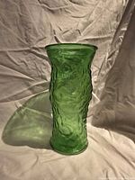 Full view of textured emerald green glass vase standing upright