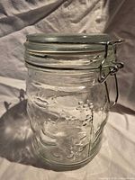 Full view of embossed glass canister, side profile showing fruit pattern